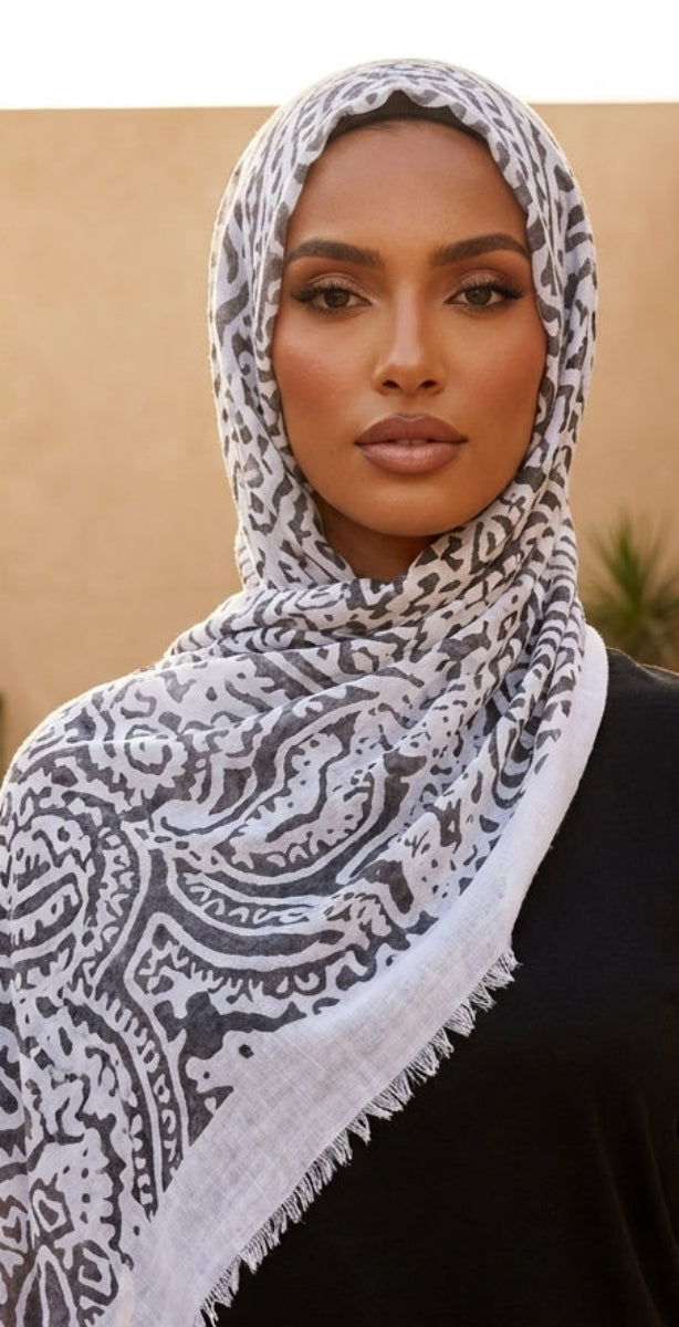 Woman wearing a patterned scarf outdoors with architectural elements in the background