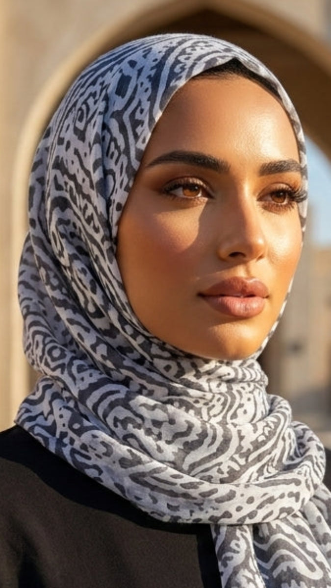 Woman wearing a patterned hijab in an outdoor setting with architectural elements.