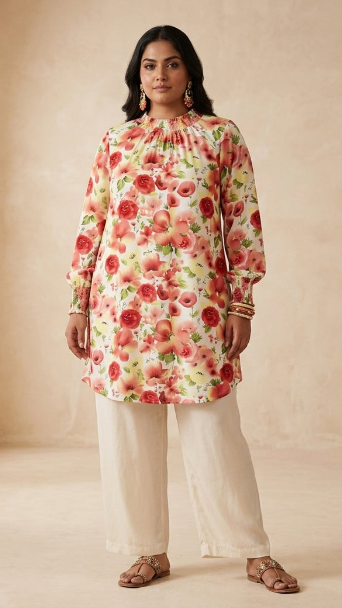 Woman wearing a floral top and white pants in a neutral setting