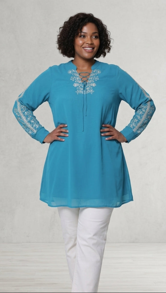 Woman wearing a turquoise top with lace sleeves against a plain background