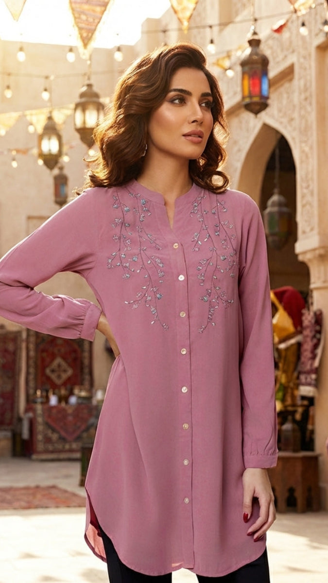 Woman wearing a pink embroidered dress in an ornate courtyard setting