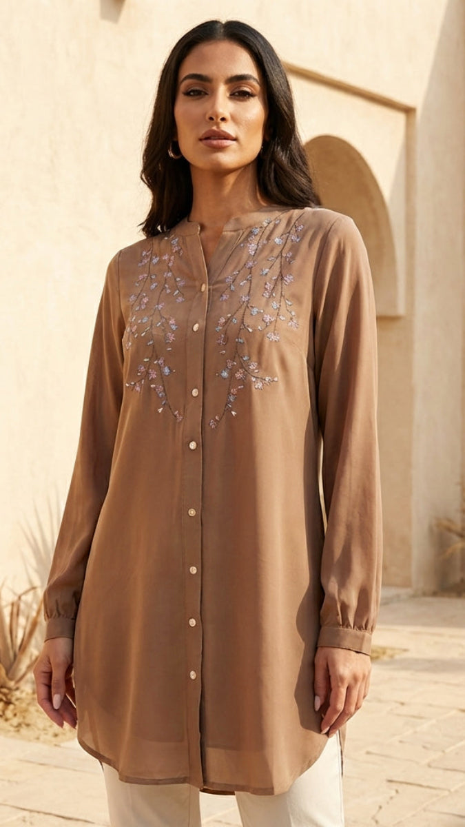 Woman wearing a brown embroidered shirt in an outdoor setting