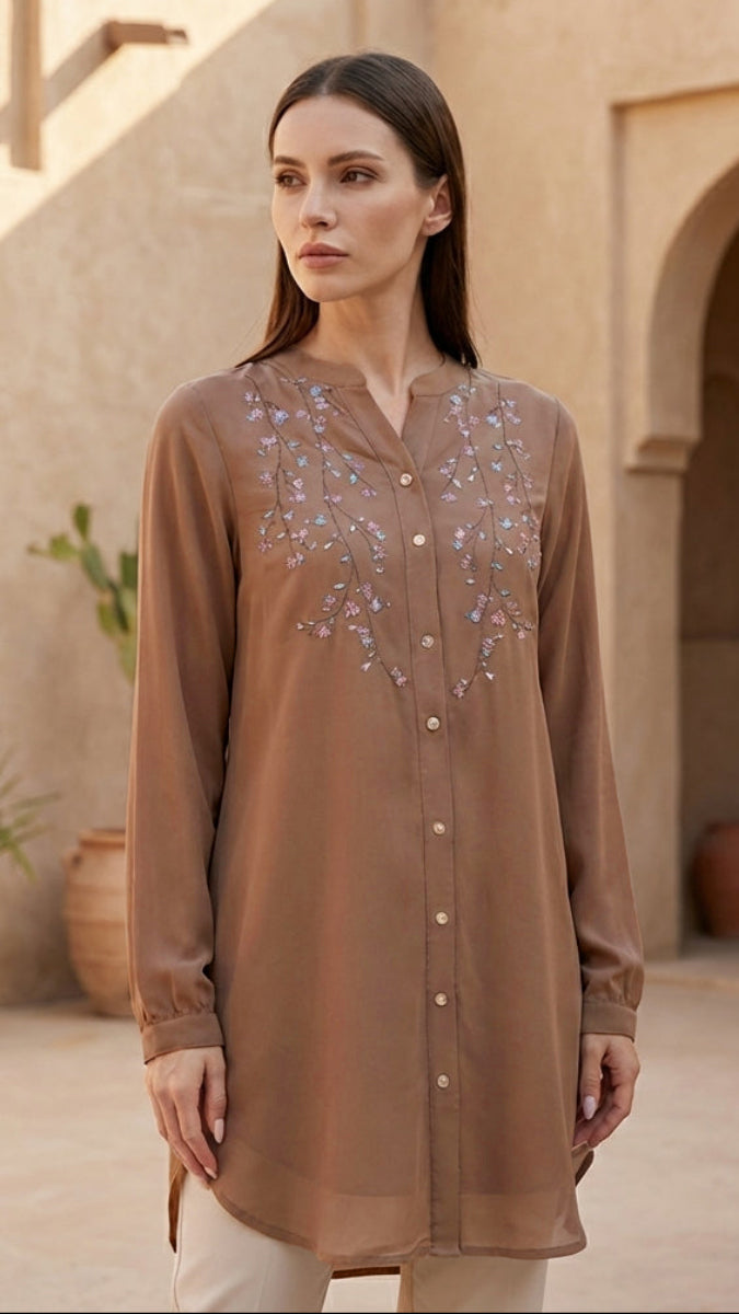 Woman wearing a brown embroidered shirt in an outdoor setting