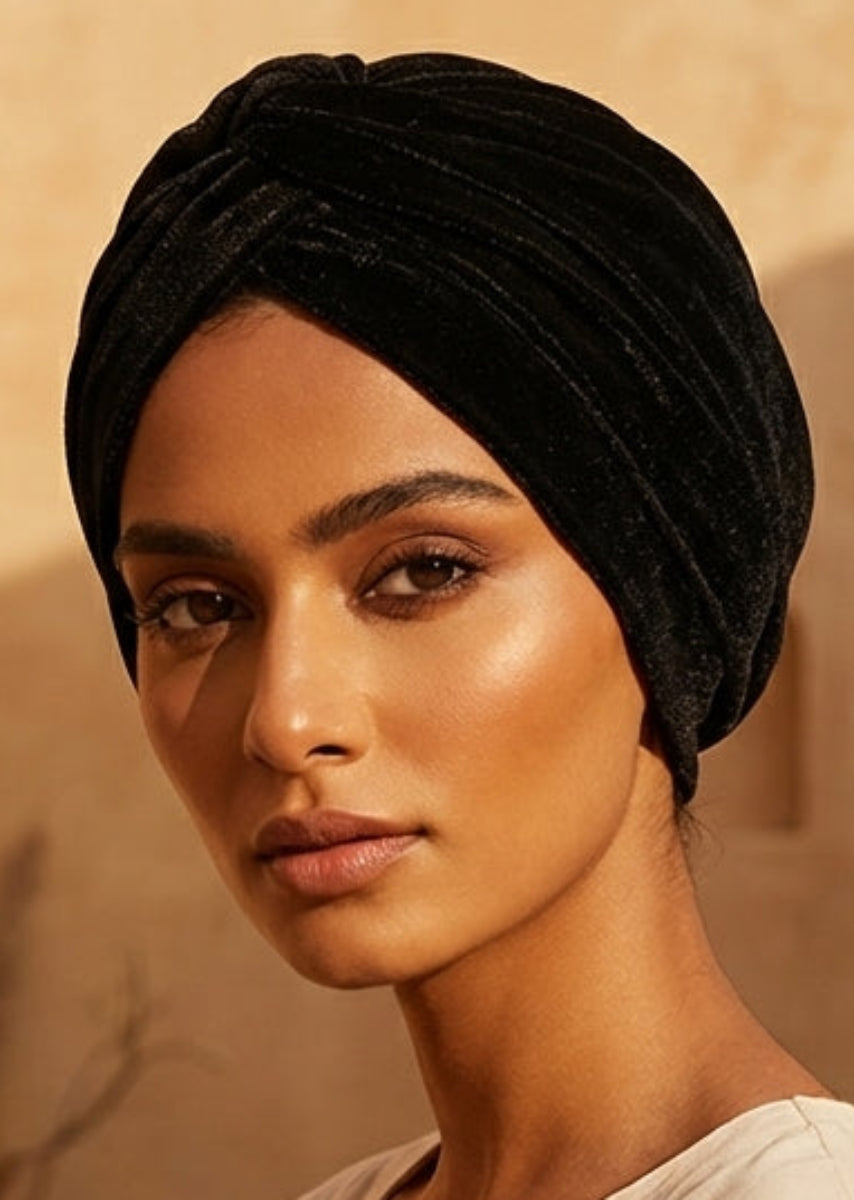 Woman wearing a black turban and beige embroidered dress in a desert setting