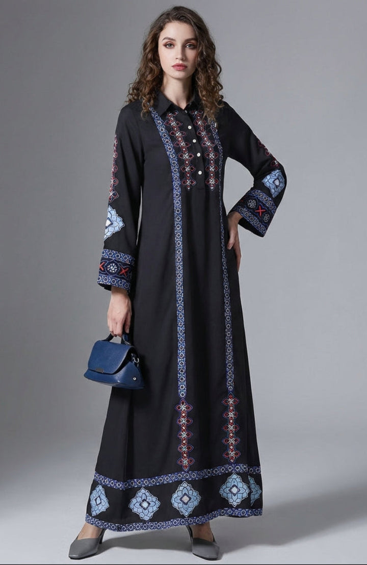 Woman wearing a black dress with blue embroidery against a gray background