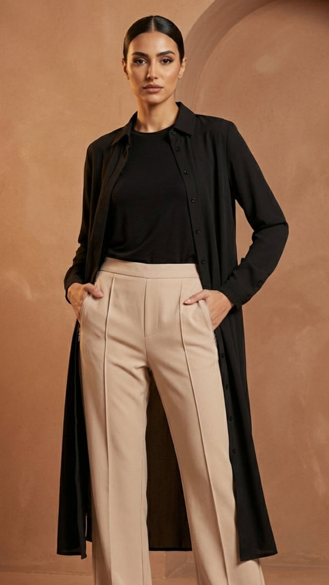 Woman wearing a black shirt and beige pants against a brown background