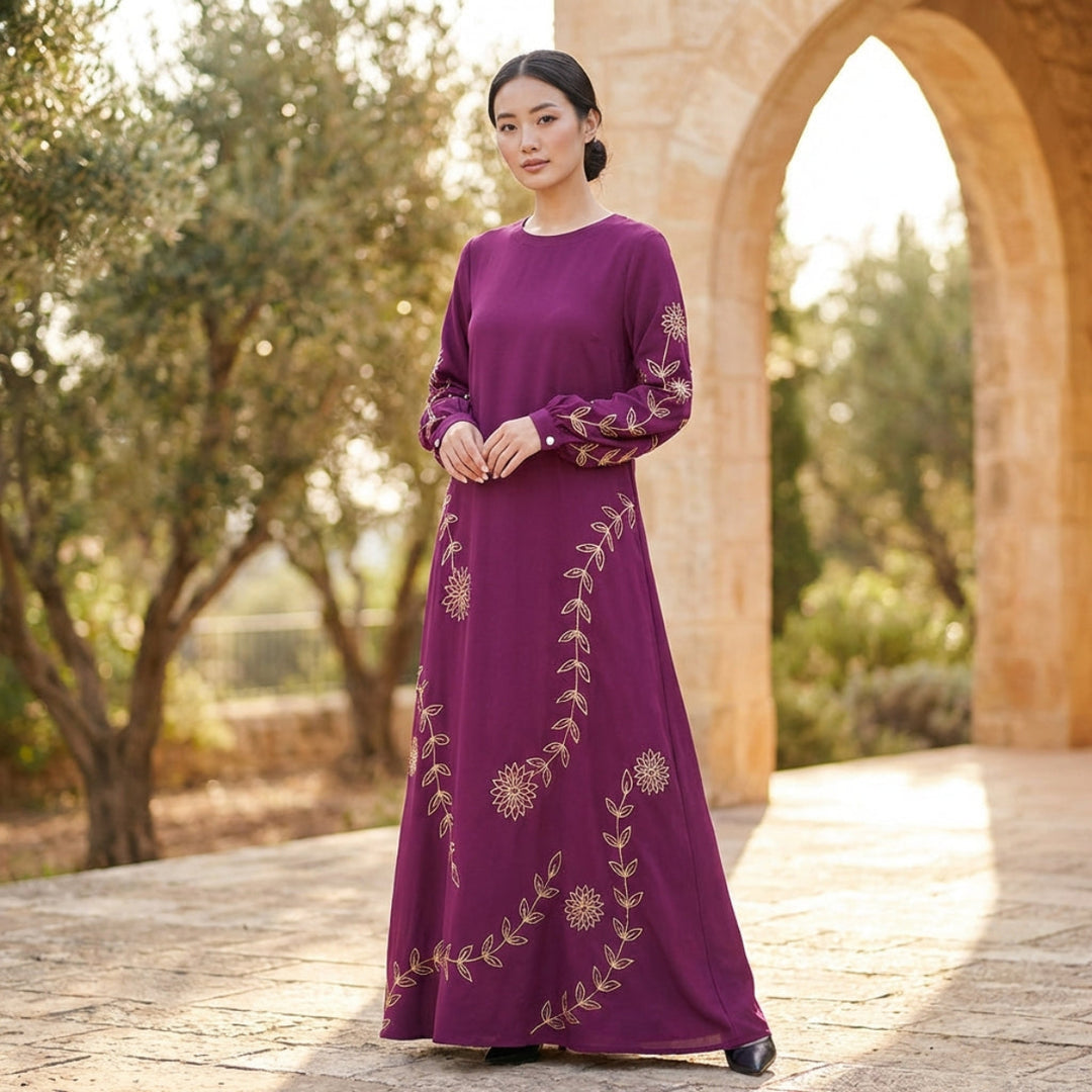 Woman wearing a purple embroidered dress standing in front of an archway with trees in the background