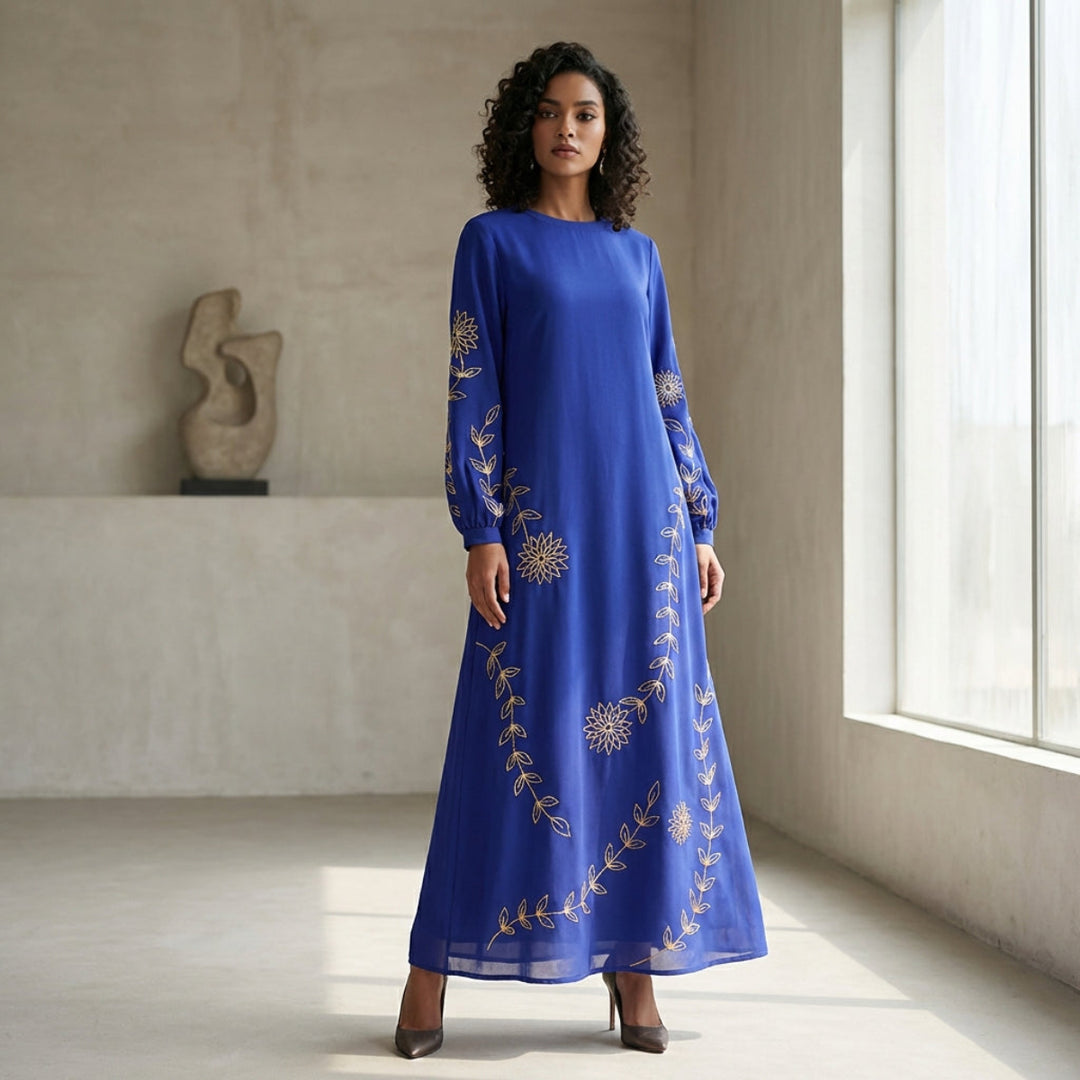 Woman wearing a blue dress with gold embroidery in a bright room.