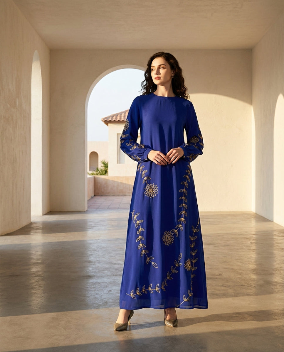 Woman wearing a blue embroidered dress standing in a sunlit hallway.