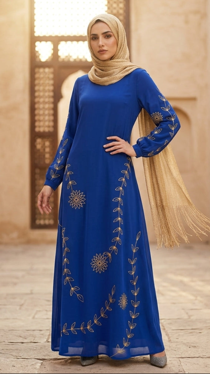 Woman in a blue dress with gold embroidery standing in a sunlit architectural setting.
