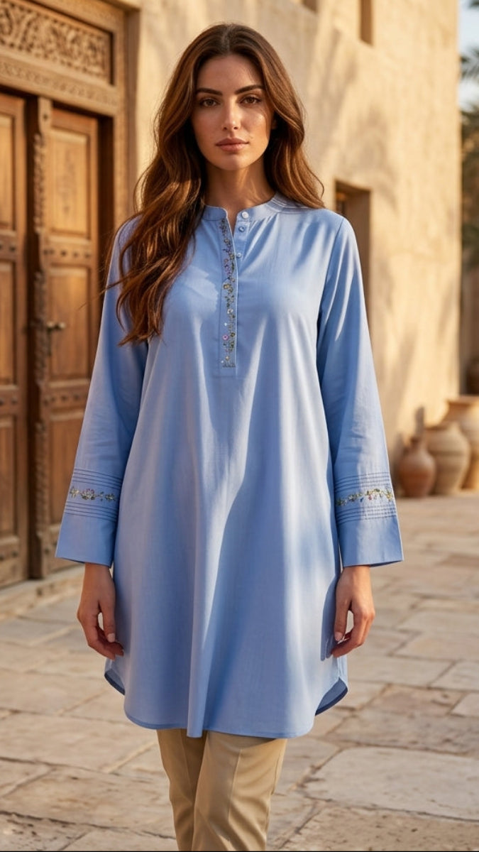 Woman wearing a light blue dress standing in front of a traditional building with wooden doors.