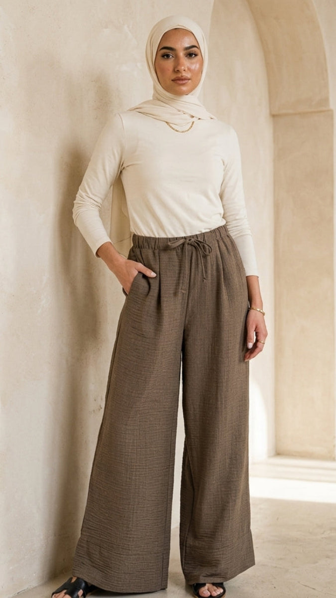 Woman wearing a white top and brown pants in an architectural setting