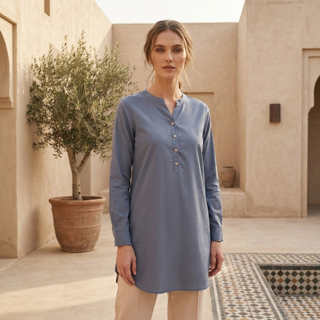 Woman wearing a blue long-sleeve shirt in a courtyard setting