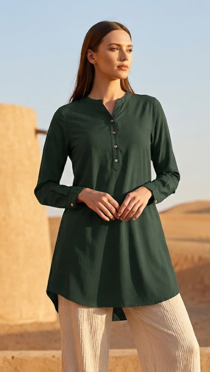 Woman in a green shirt standing in front of ancient stone architecture with desert landscape in the background