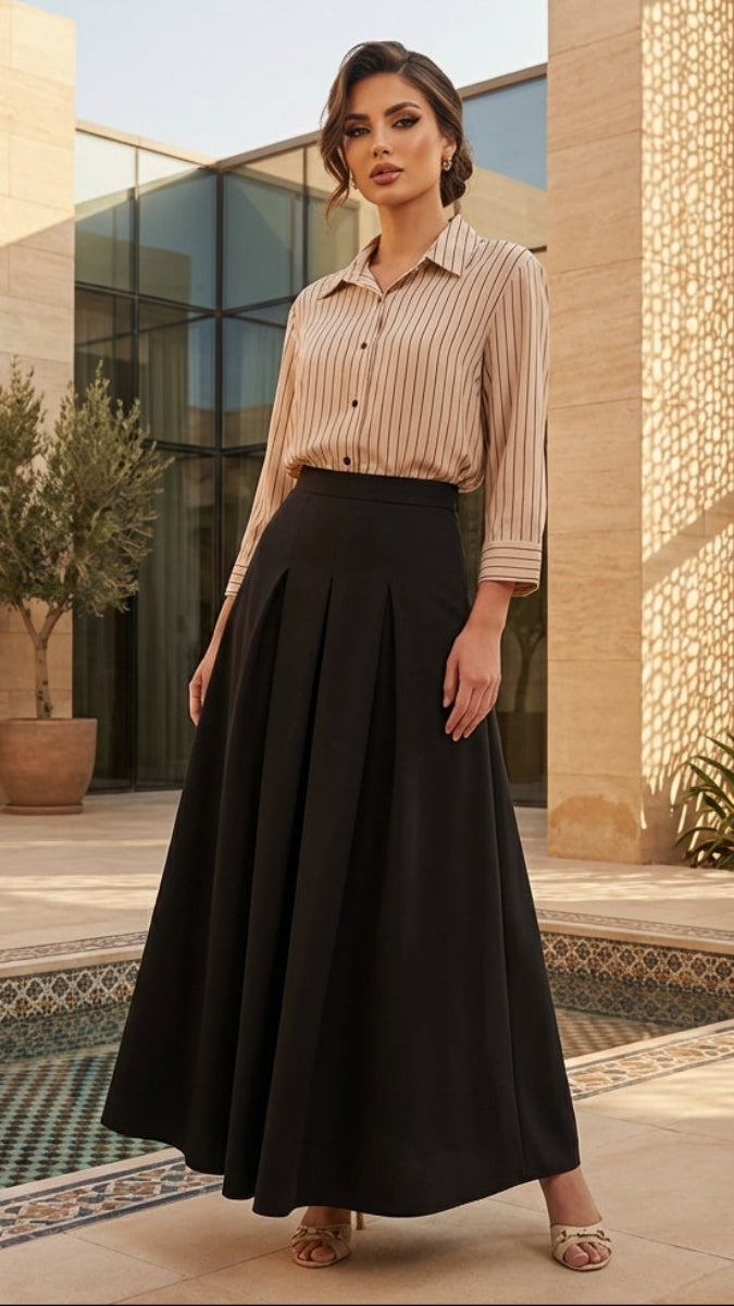 Woman in a beige blouse and black skirt standing in an outdoor setting with architectural elements and plants.