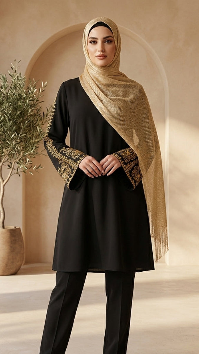 Woman wearing a black outfit with gold embroidery in a beige interior setting
