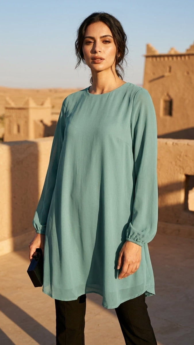 Woman wearing a light blue dress standing in front of a traditional building with a clear sky.
