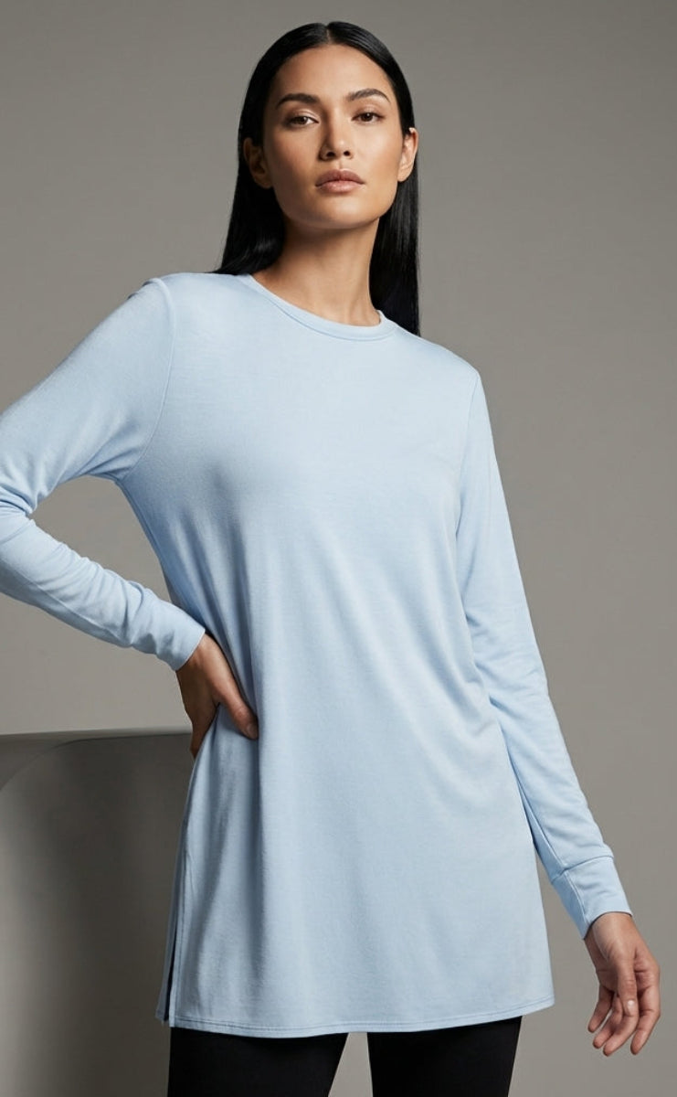 Woman wearing a light blue long-sleeve dress against a gray background