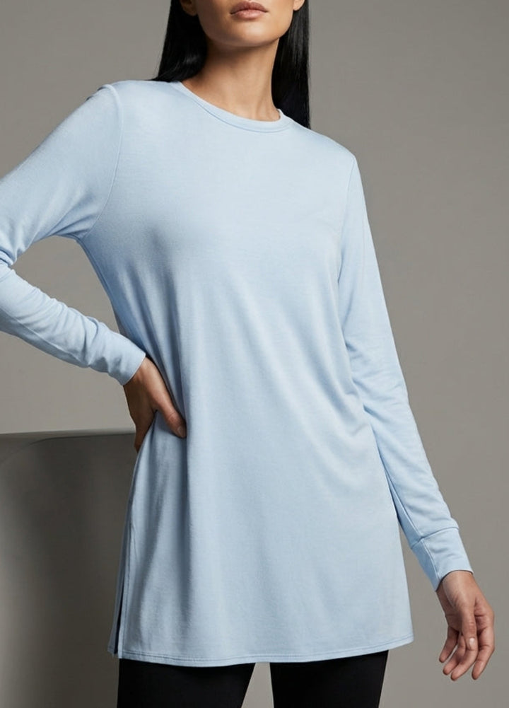 Woman wearing a light blue long-sleeve dress against a gray background