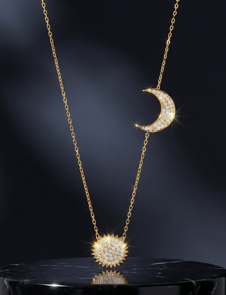 Gold necklace with moon and sun pendants on a dark background
