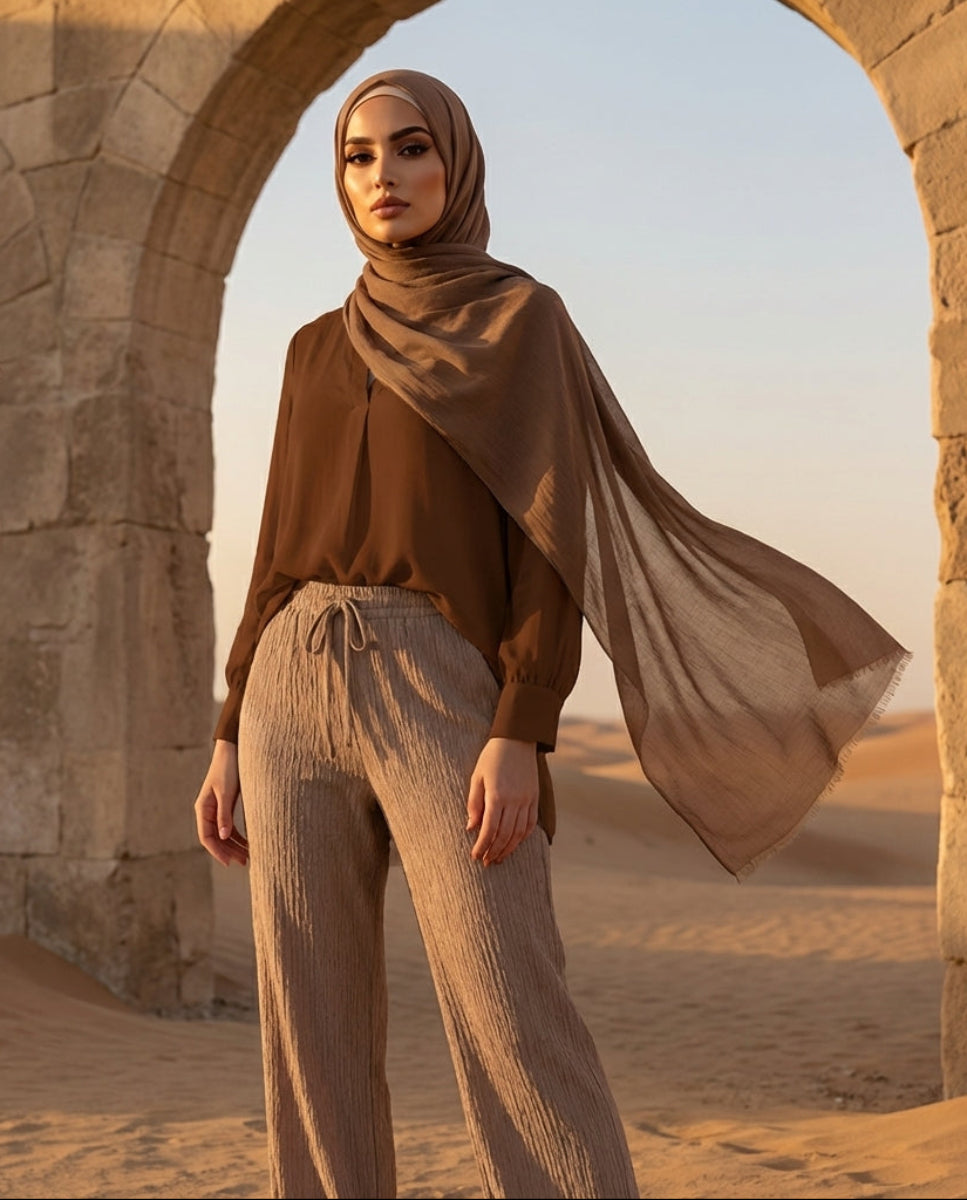 Woman in a hijab standing in a desert with stone arches