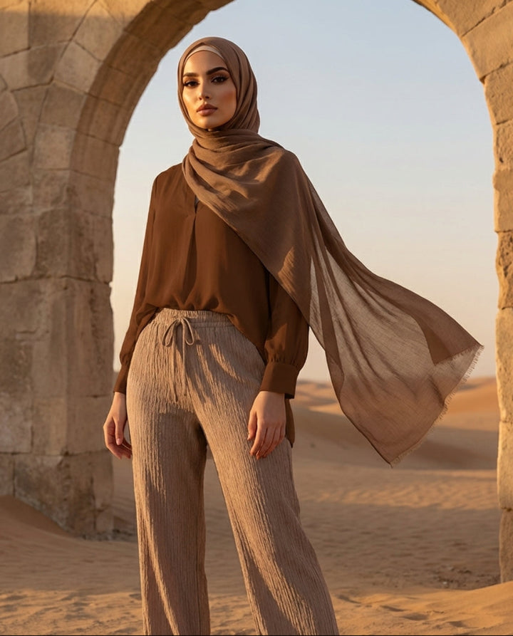 Woman in a hijab standing in a desert with stone arches