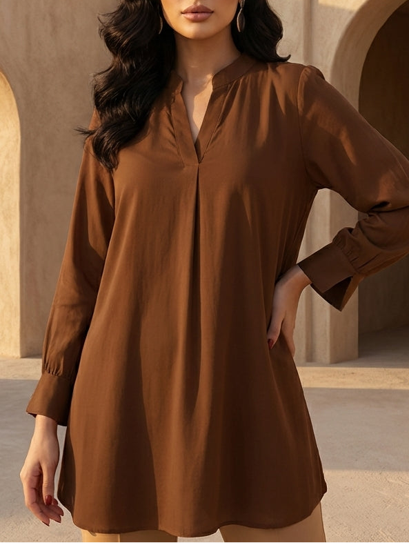 Woman in a brown dress standing in a desert setting with arches.