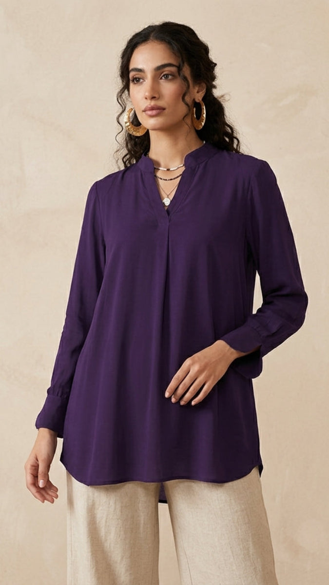 Woman wearing a purple blouse against a beige background