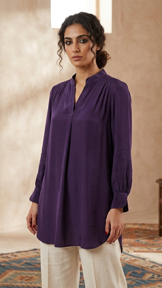 Woman wearing a purple blouse in an indoor setting with a neutral background
