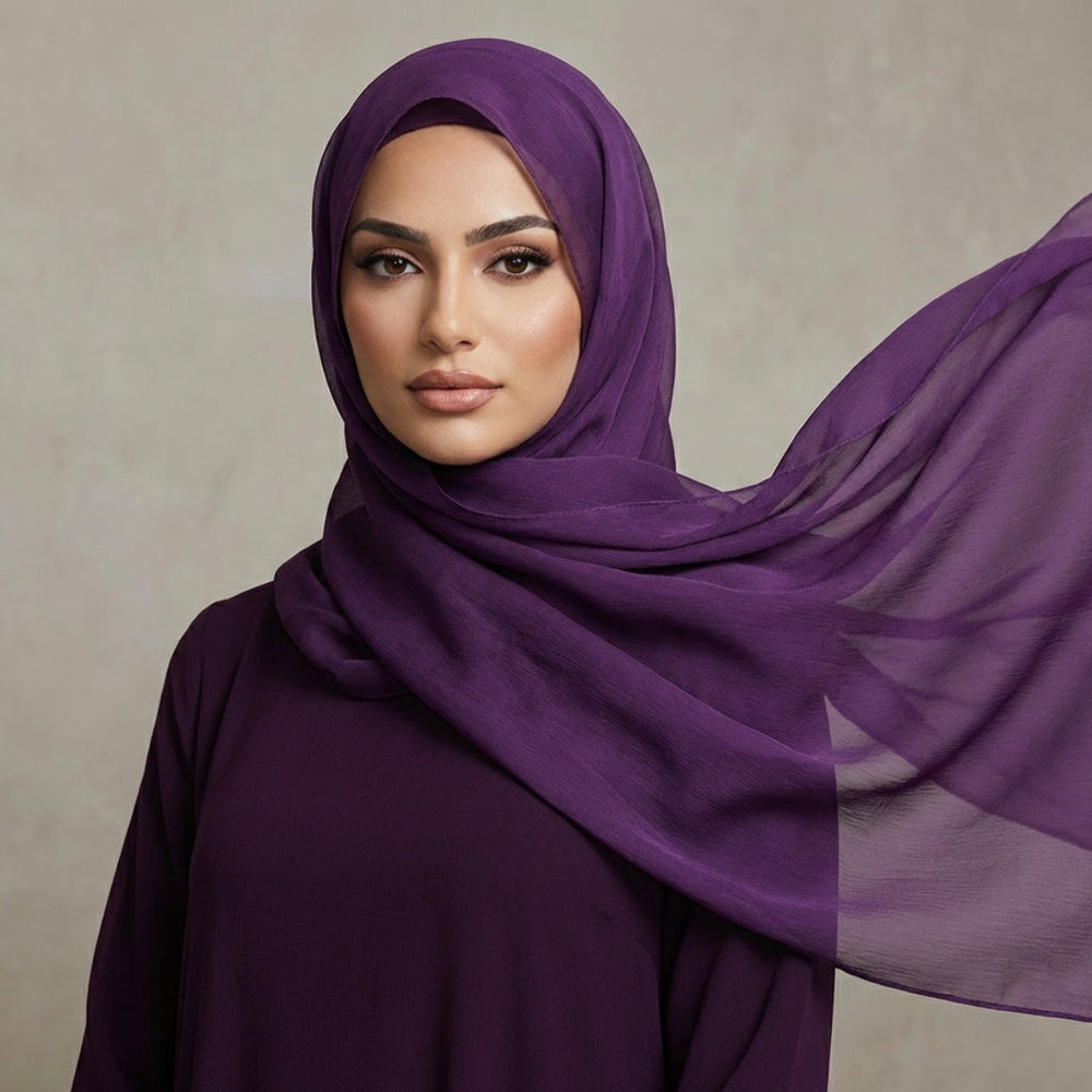 Woman wearing a purple hijab against a neutral background