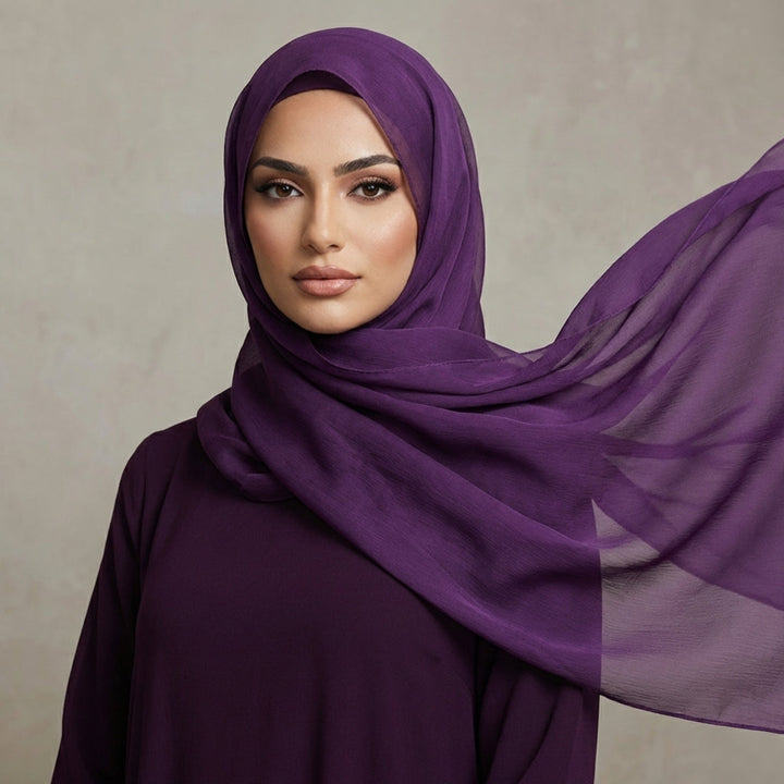 Woman wearing a purple hijab against a neutral background