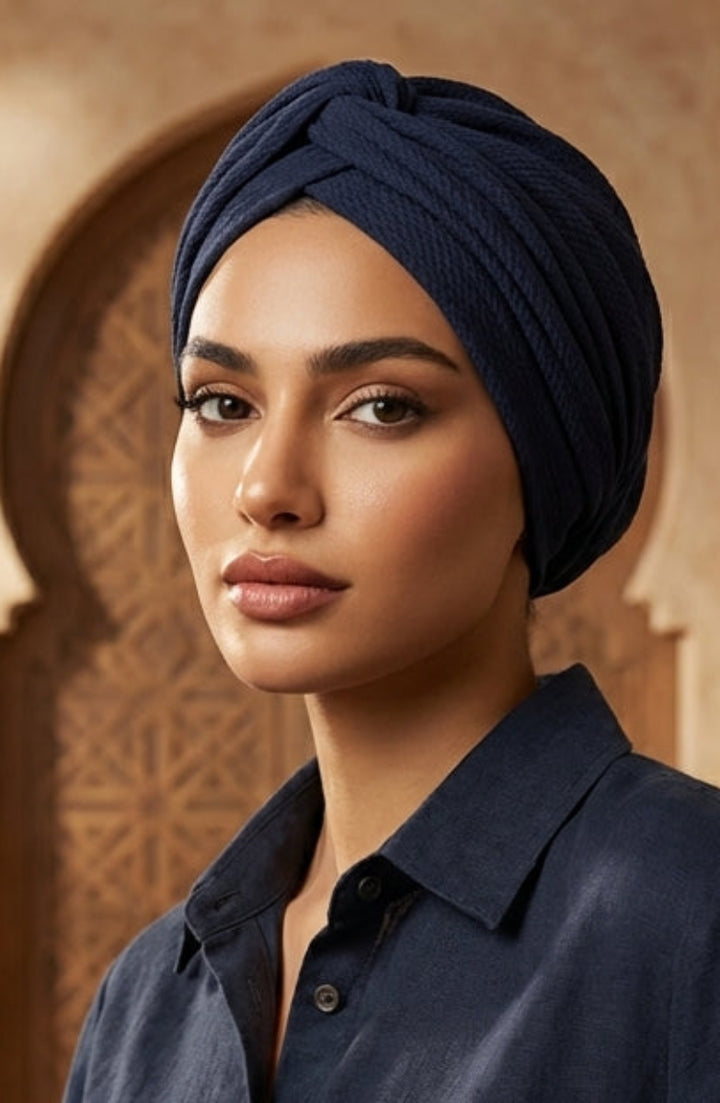 Woman wearing a navy blue shirt and headscarf in an ornate interior setting