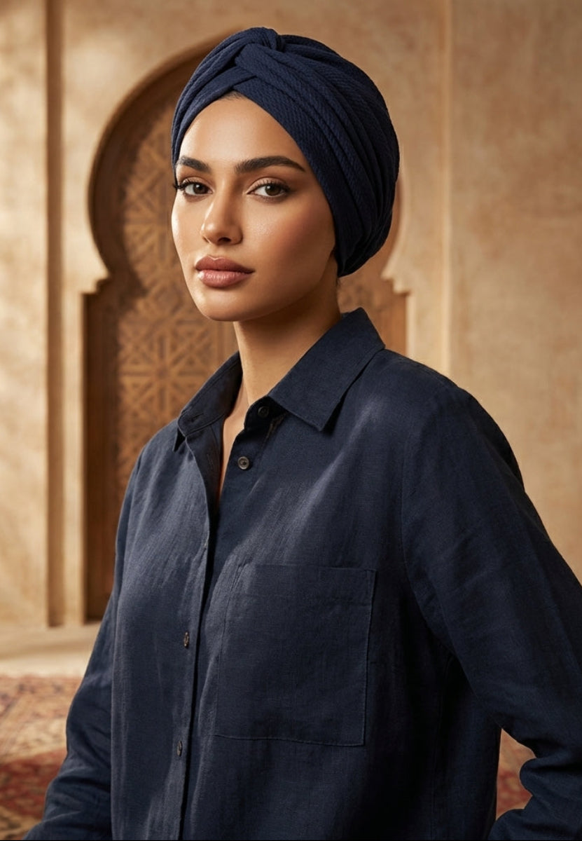 Woman wearing a navy blue shirt and headscarf in an ornate interior setting