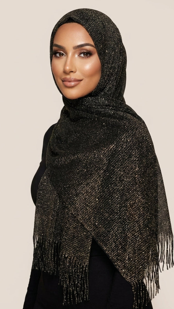 Woman wearing a black and gold patterned scarf with fringe on a beige background