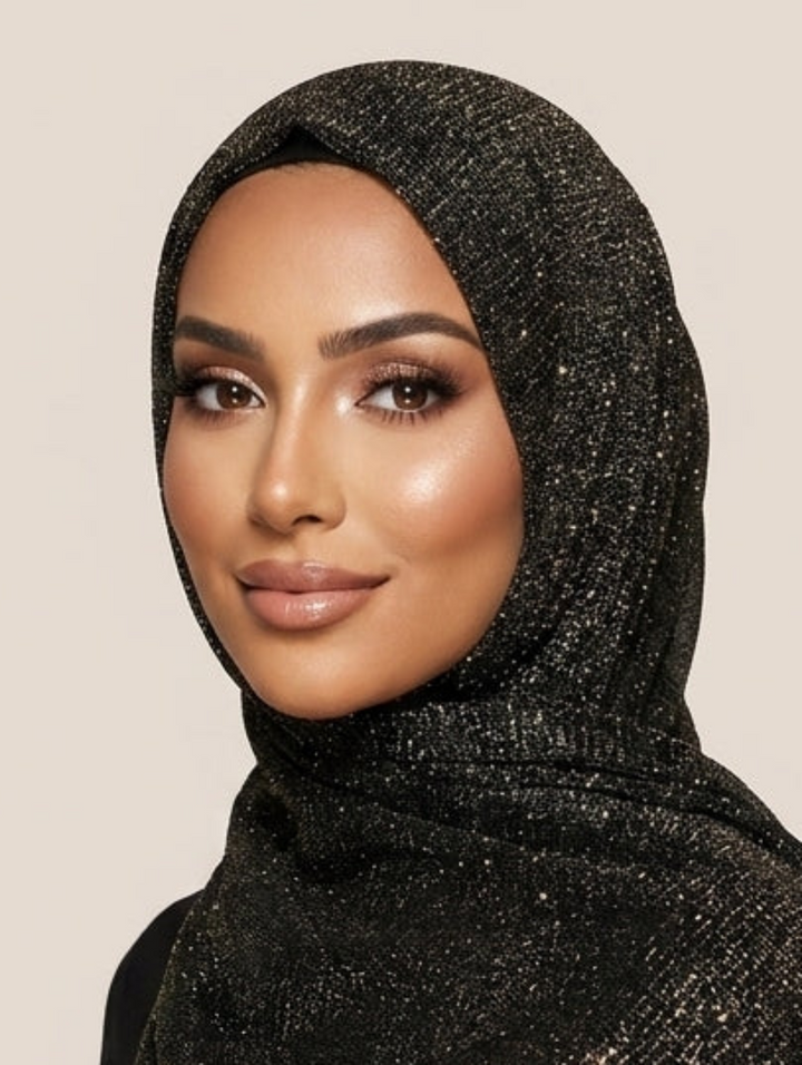 Woman wearing a black and gold patterned scarf with fringe on a beige background