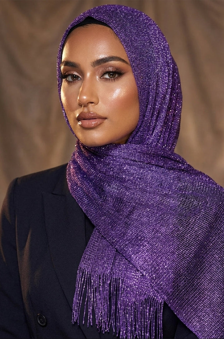Woman wearing a purple scarf with fringe details against a neutral background