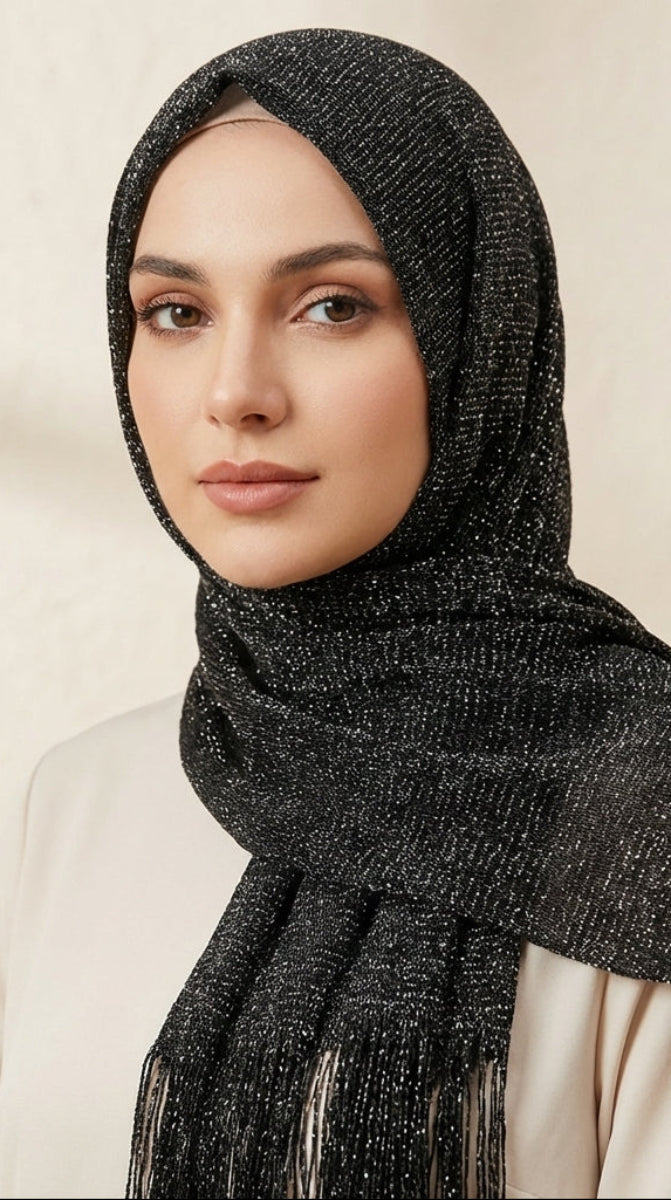 Woman wearing a black textured hijab with fringe details against a neutral background