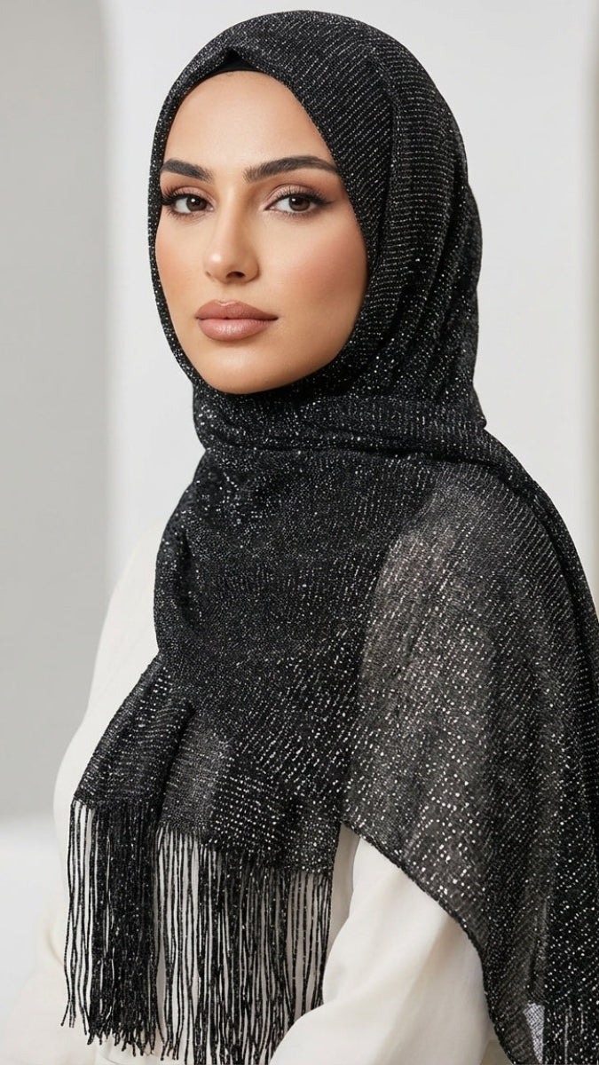 Woman wearing a black hijab with fringe details against a neutral background