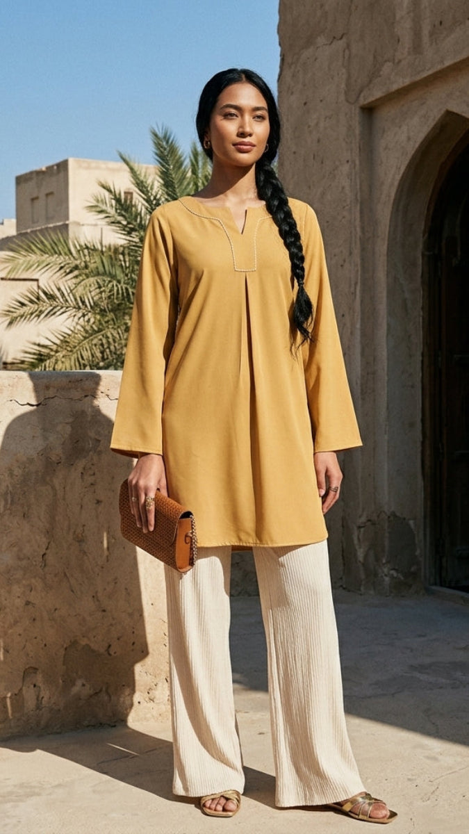 Woman in a yellow dress standing in front of a stone building with palm trees in the background