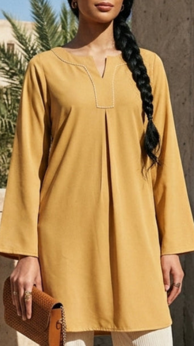 Woman wearing a mustard yellow dress with a braided hairstyle, standing outdoors.
