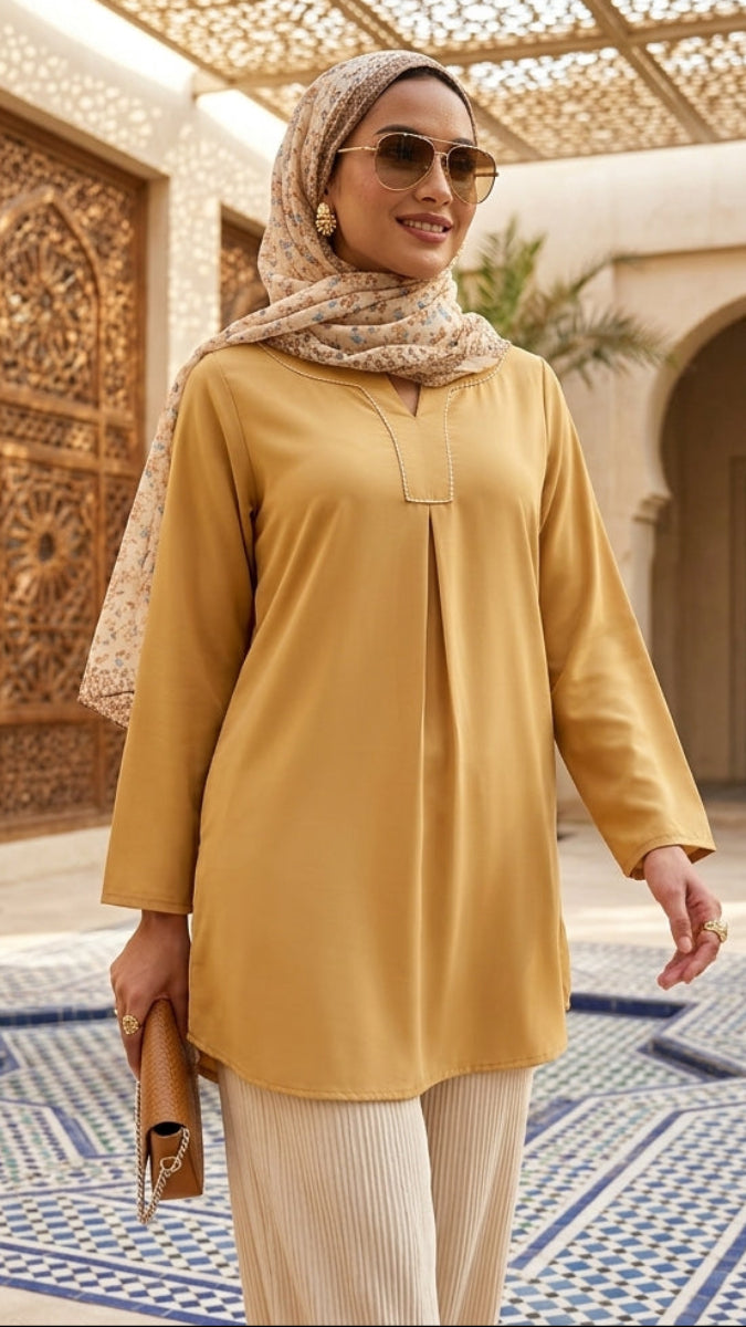 Woman in a yellow top and hijab standing in a decorative courtyard.