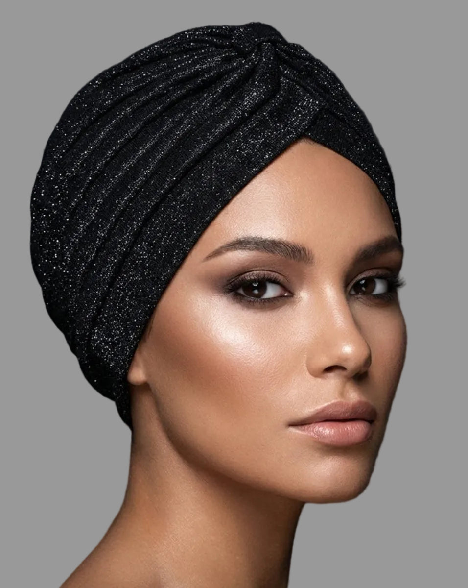 Woman wearing a black glittery headscarf against a dark background