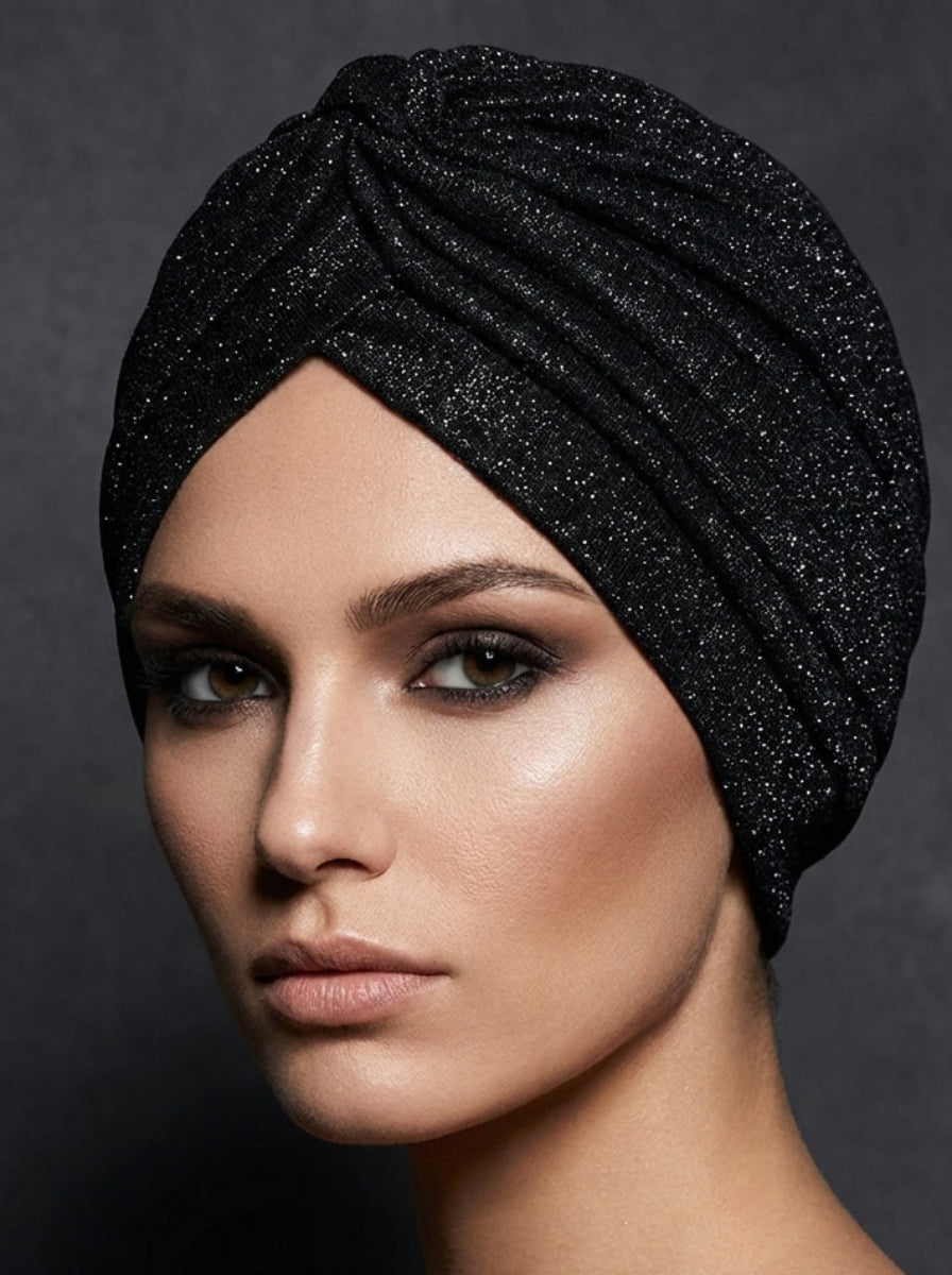 Woman wearing a black glittery headscarf against a dark background