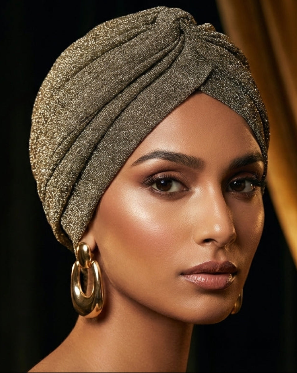 Woman wearing a textured headscarf with gold earrings against a dark background