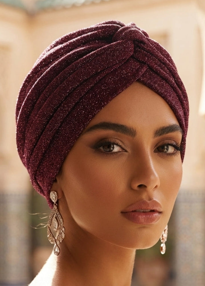 Woman wearing a maroon turban in an ornate architectural setting