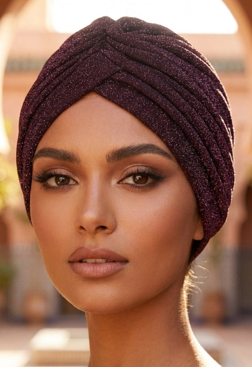 Woman wearing a dark purple turban in a warm-toned outdoor setting