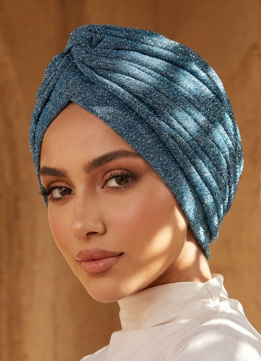 Woman wearing a blue turban in front of an architectural background