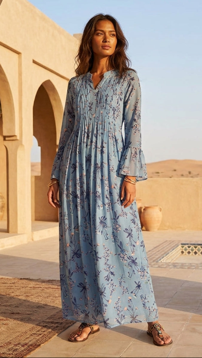 Woman in a long blue dress standing in a desert setting with arches and a clear sky.