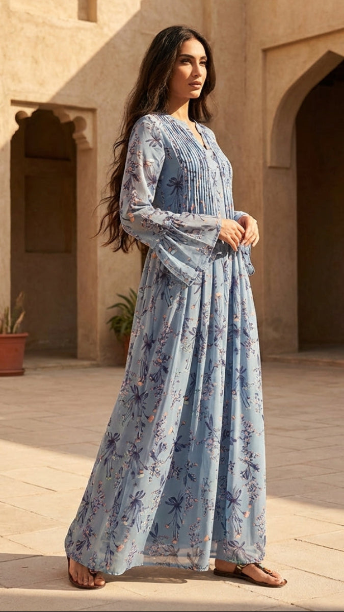 Woman in a blue floral dress standing in a sunlit courtyard with arches and plants.
