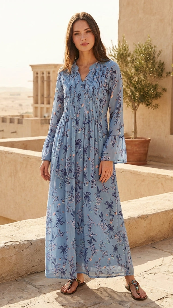 Woman in a blue floral dress standing on a stone patio with a desert landscape in the background